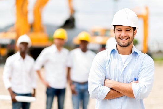 3 blurred construction workers in the background and one in focus in the foreground