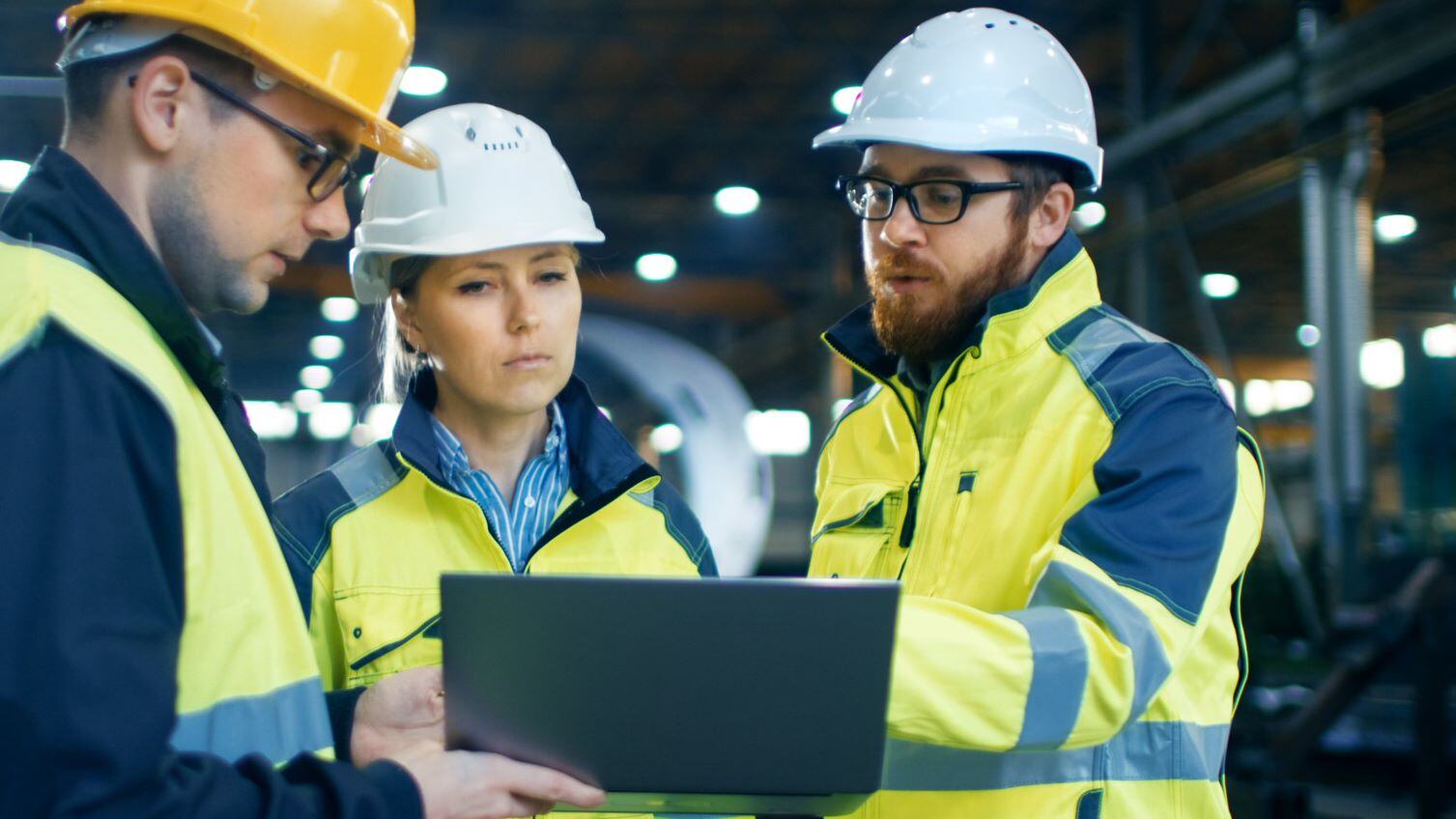 Workers wearing hard hats looking at tablet